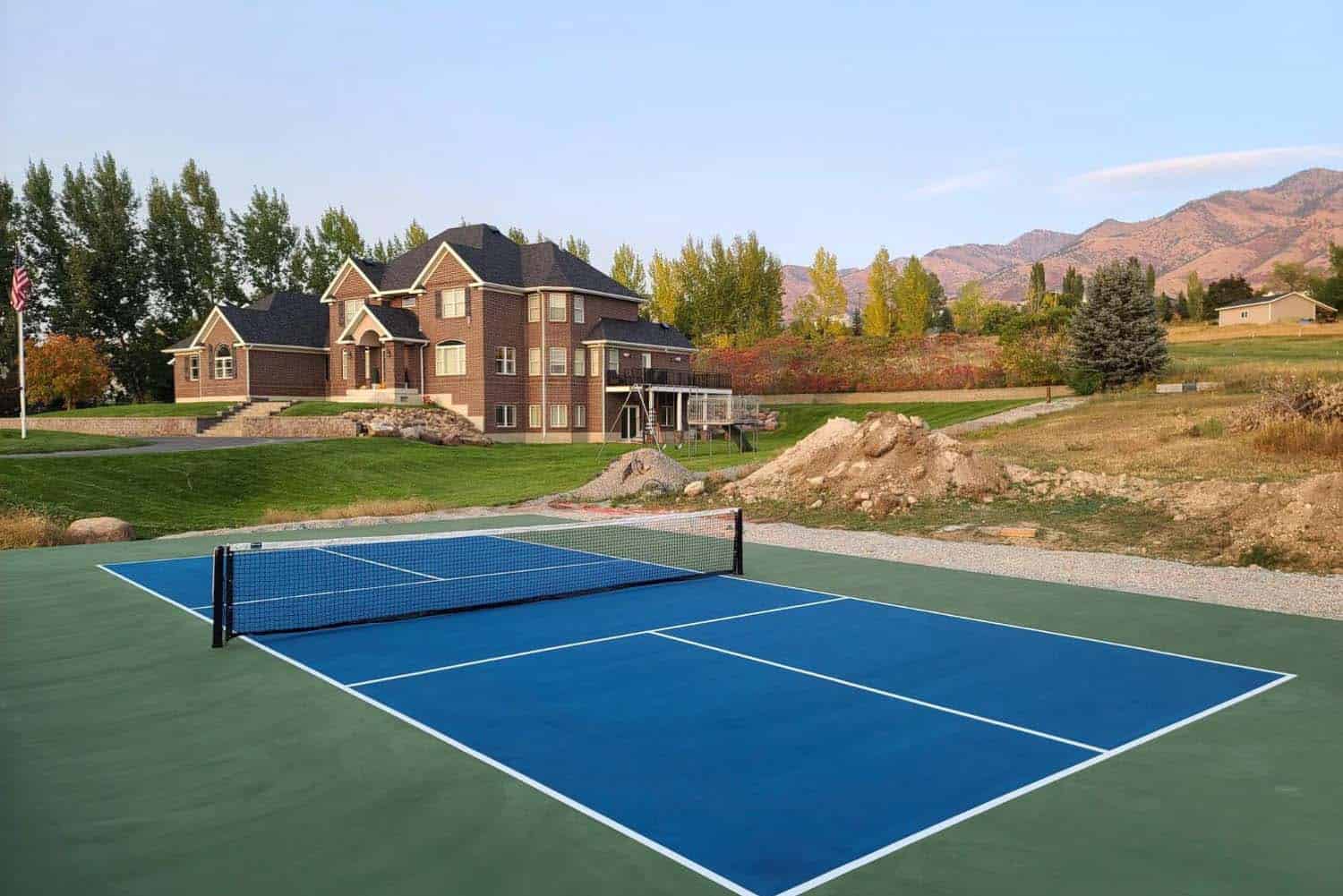 Tennis court installation at a luxury home with mountain views and landscaped surroundings.